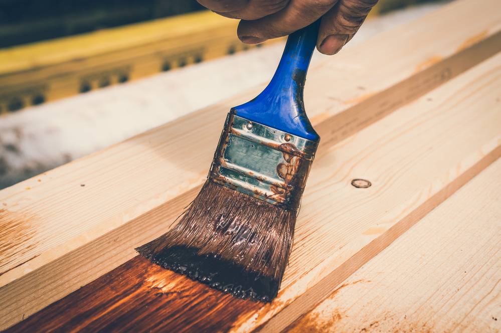 person applying wood staining to planks